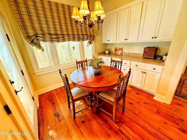 dining room featuring a chandelier, light wood-type flooring, and baseboards