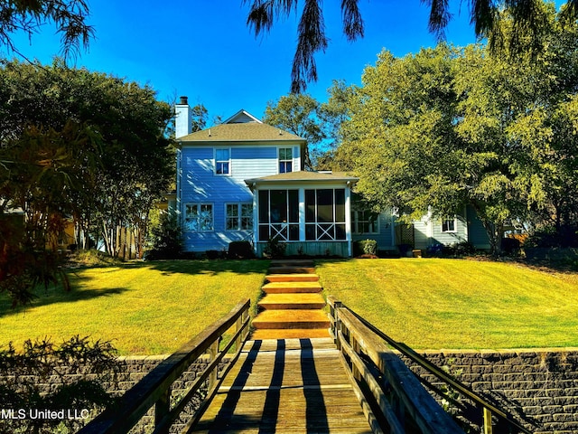 rear view of house with a yard and a sunroom