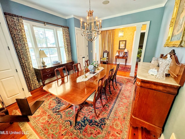 dining space featuring crown molding, hardwood / wood-style floors, and a notable chandelier