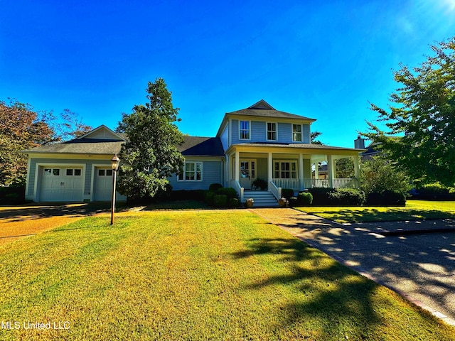 view of front of home featuring covered porch, a garage, and a front lawn