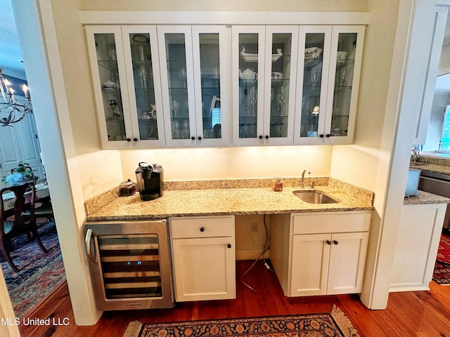 bar featuring dark wood-type flooring, white cabinets, sink, and beverage cooler