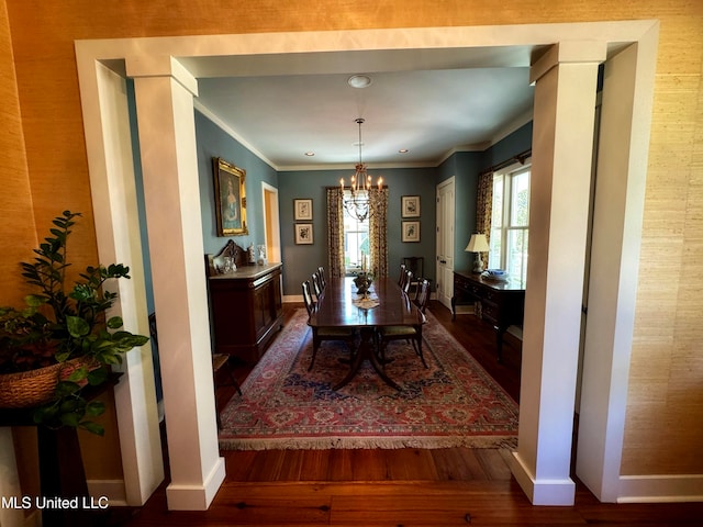 dining room with crown molding, a chandelier, and dark wood-type flooring