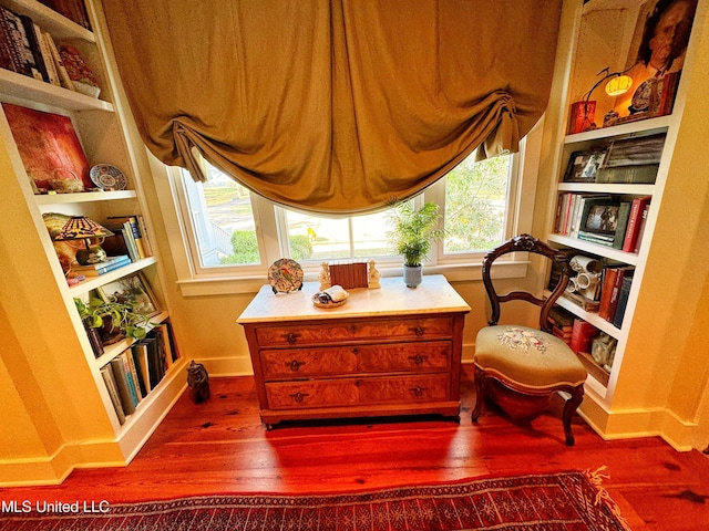 sitting room with dark wood-style flooring, baseboards, and built in features
