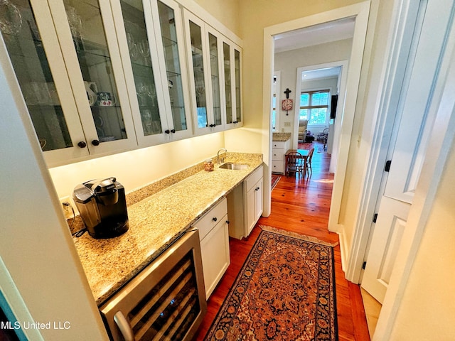 interior space with light stone countertops, sink, white cabinetry, wine cooler, and dark hardwood / wood-style floors