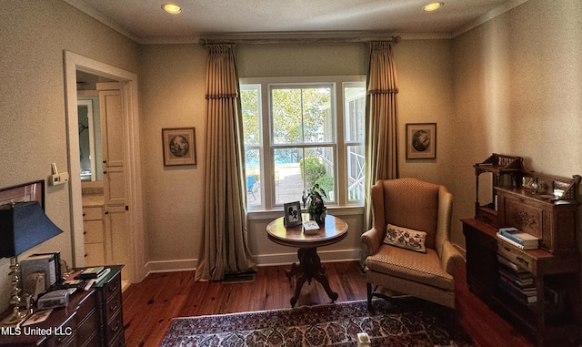 sitting room featuring wood finished floors, baseboards, a textured wall, ornamental molding, and recessed lighting
