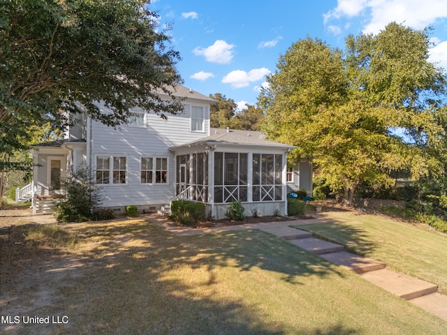 back of property with a yard and a sunroom