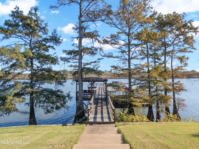 view of dock with a lawn and a water view