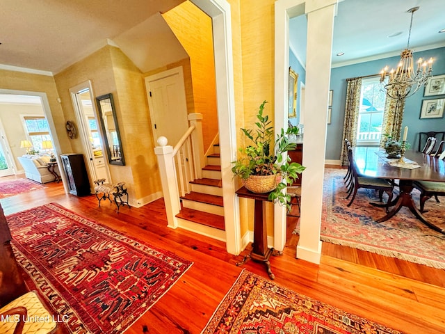 entrance foyer with crown molding, hardwood / wood-style flooring, and a chandelier