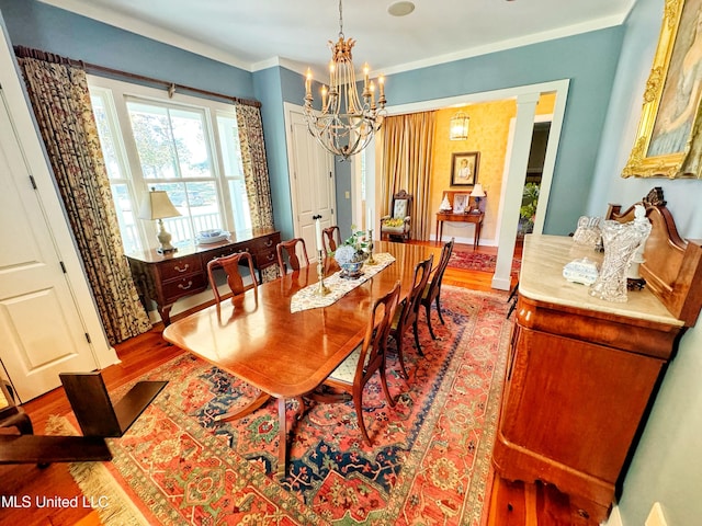 dining space with wood finished floors, a chandelier, and ornamental molding