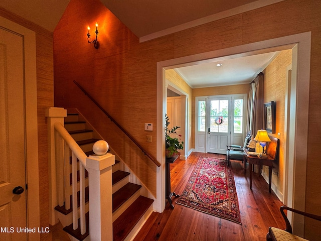 foyer featuring hardwood / wood-style flooring, stairway, baseboards, and crown molding