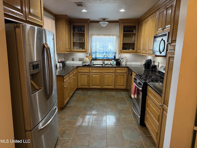 kitchen featuring stainless steel appliances, sink, and dark stone countertops