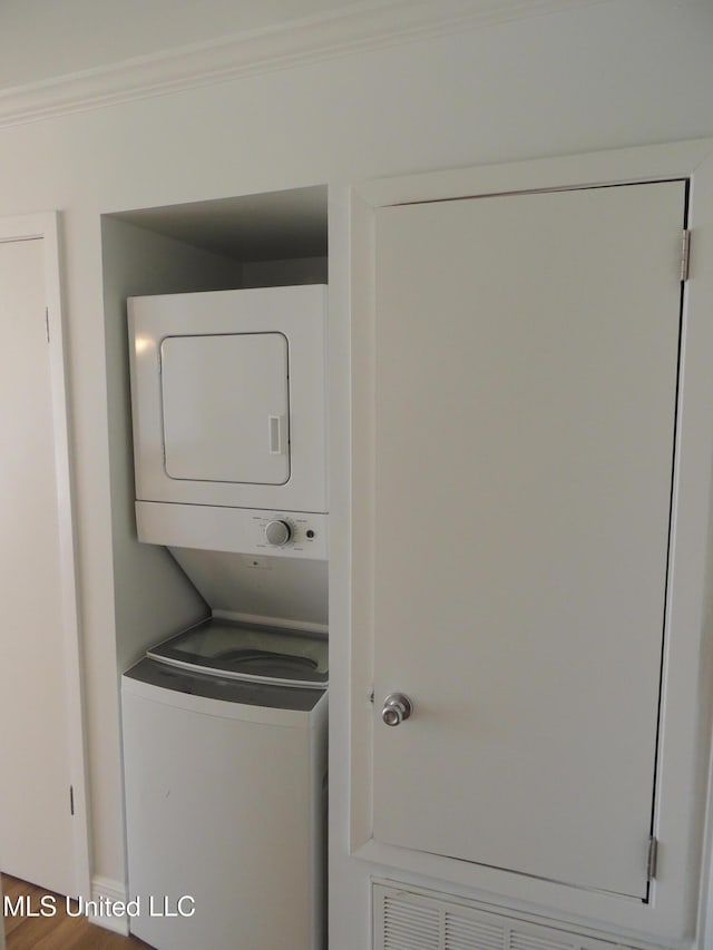 laundry area featuring stacked washer and dryer, laundry area, and crown molding