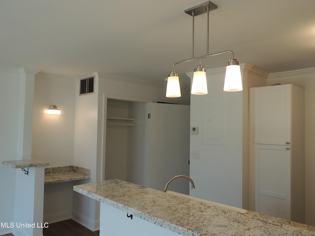 kitchen with light stone counters, pendant lighting, crown molding, visible vents, and a sink