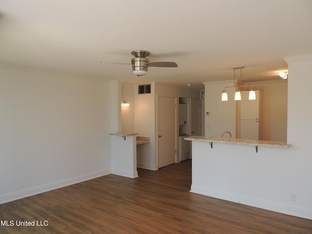 kitchen with baseboards, visible vents, dark wood-style floors, a peninsula, and crown molding