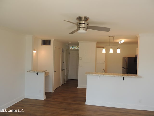 kitchen with visible vents, dark wood-style floors, ornamental molding, freestanding refrigerator, and a peninsula