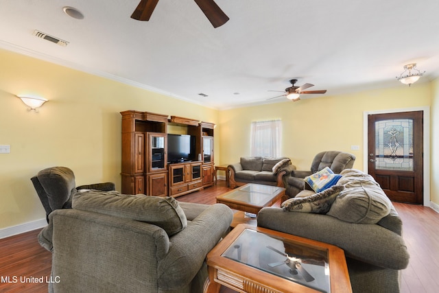 living area featuring baseboards, visible vents, a ceiling fan, ornamental molding, and wood finished floors