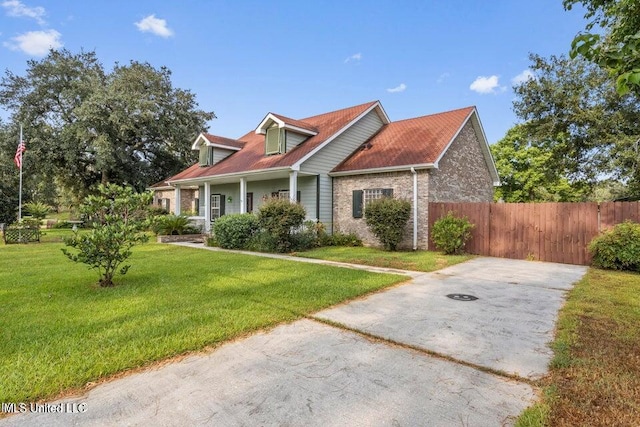 cape cod home with brick siding, a front yard, and fence