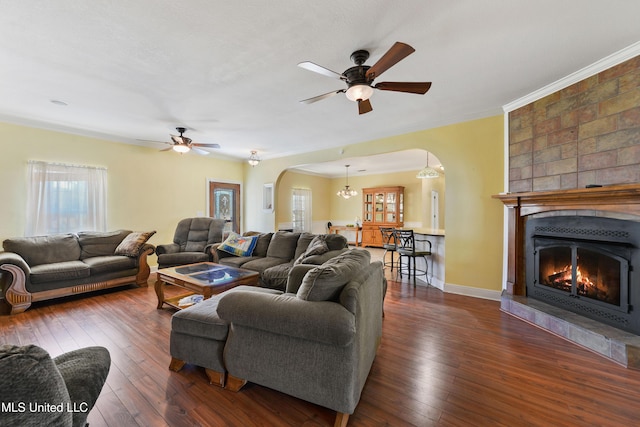 living area featuring arched walkways, ceiling fan, dark wood-style flooring, and baseboards