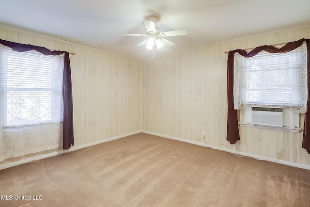 spare room featuring light colored carpet, wood walls, ceiling fan, and cooling unit