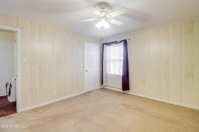 unfurnished room featuring wood walls, ceiling fan, and light carpet