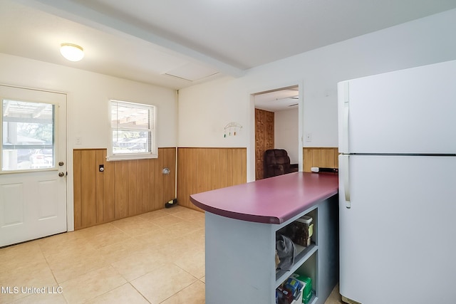 kitchen featuring wooden walls, white fridge, and beamed ceiling