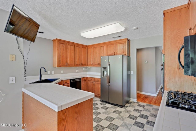 kitchen with sink, black appliances, kitchen peninsula, and a textured ceiling