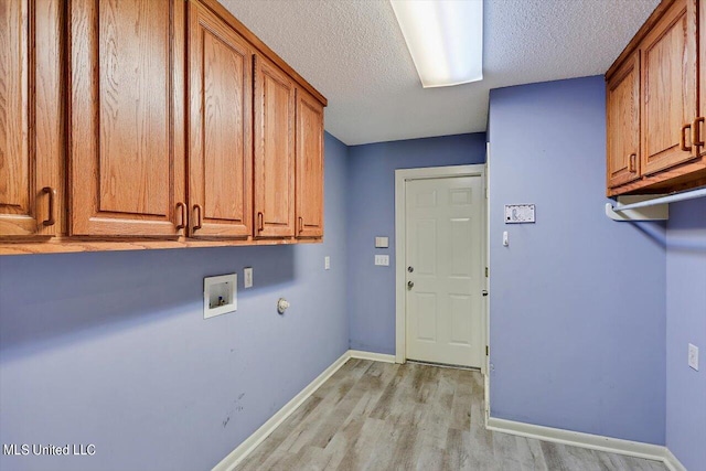 washroom featuring cabinets, light hardwood / wood-style flooring, a textured ceiling, and washer hookup