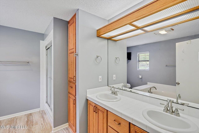 bathroom featuring vanity, wood-type flooring, a textured ceiling, and independent shower and bath