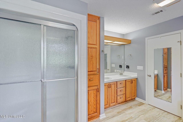 bathroom with a shower with door, vanity, hardwood / wood-style floors, and a textured ceiling