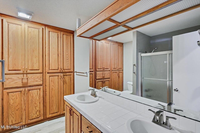 bathroom featuring a textured ceiling, wood-type flooring, toilet, vanity, and an enclosed shower