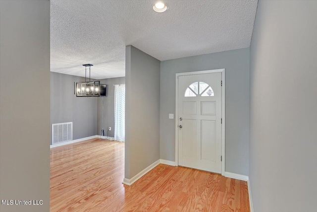 entryway featuring a textured ceiling and light hardwood / wood-style flooring