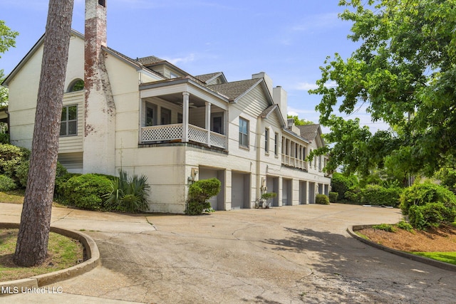 107 Lakepointe Dr, Madison, MS 39110 - view of property exterior featuring a chimney, concrete driveway, an attached garage, brick siding, and a balcony