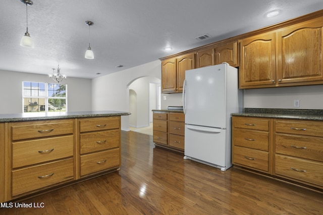 148 Acacia Ave, Biloxi, MS 39530 - kitchen with freestanding refrigerator, arched walkways, dark countertops, dark wood-style flooring, and brown cabinetry