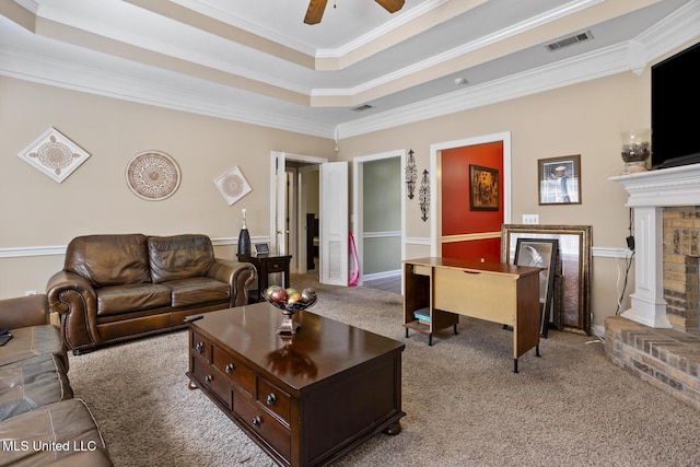 carpeted living room with a raised ceiling, ornamental molding, a ceiling fan, and a fireplace