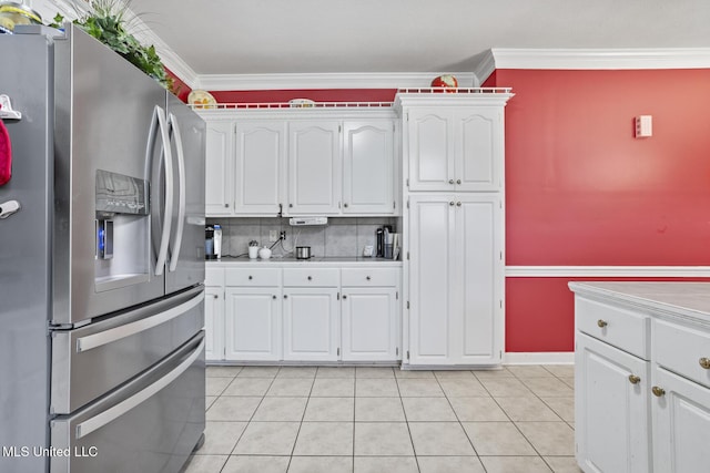 kitchen with stainless steel refrigerator with ice dispenser, white cabinetry, ornamental molding, light tile patterned flooring, and light countertops