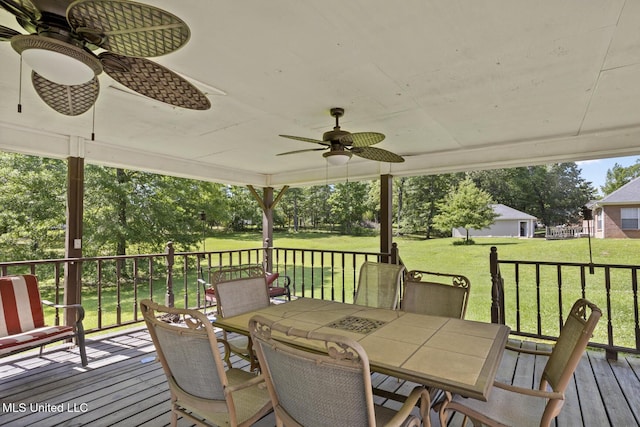 wooden deck featuring ceiling fan, outdoor dining area, and a yard