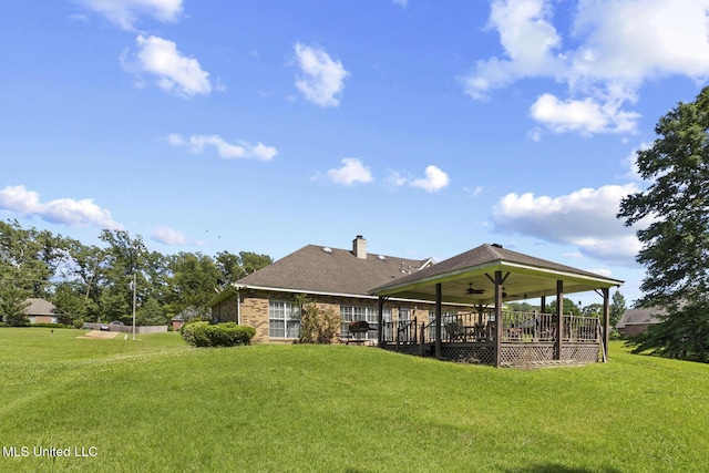 back of house with a ceiling fan, a lawn, and a chimney