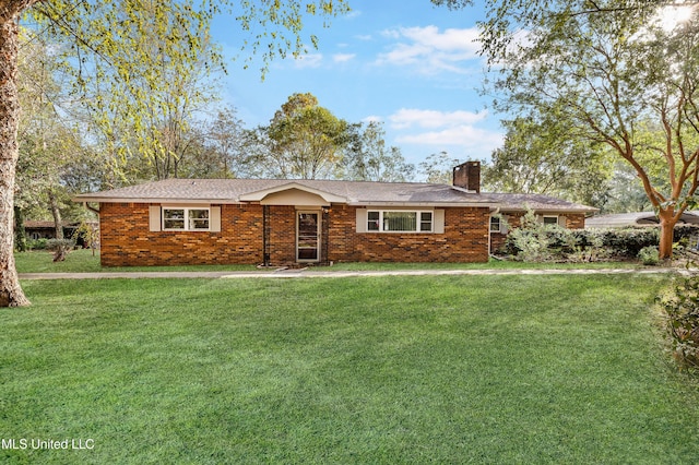 ranch-style home with a front yard, brick siding, and a chimney