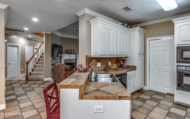 350 Edgewood Xing, Brandon, MS 39042 - kitchen featuring a fireplace, black appliances, a peninsula, white cabinetry, and decorative backsplash