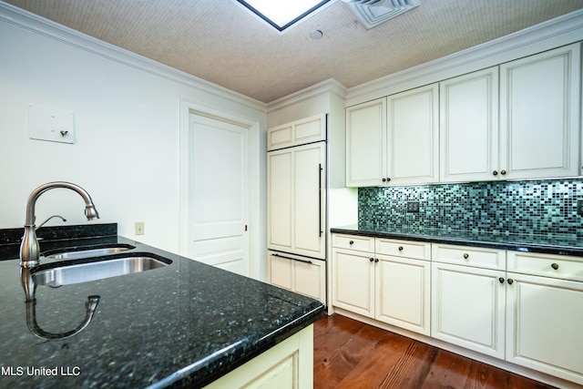 kitchen with decorative backsplash, dark wood-type flooring, dark stone countertops, sink, and crown molding