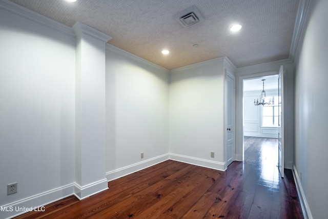 spare room with an inviting chandelier, ornamental molding, and dark hardwood / wood-style flooring