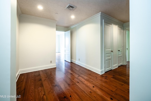 spare room featuring visible vents, baseboards, ornamental molding, and dark wood-type flooring