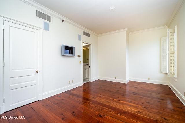 empty room with baseboards, crown molding, visible vents, and hardwood / wood-style flooring