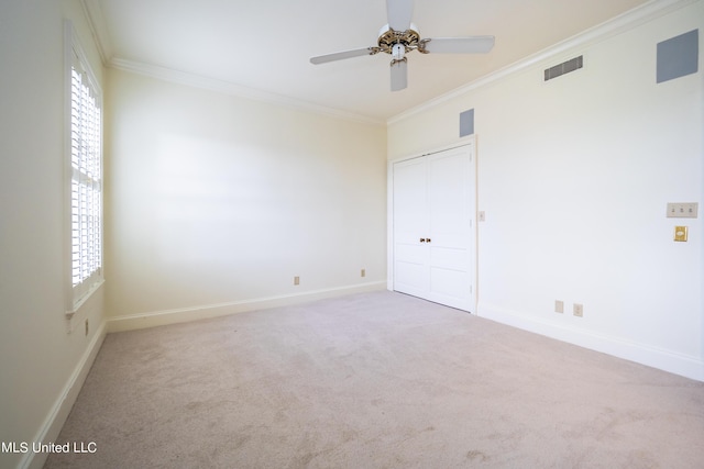 empty room featuring ornamental molding, carpet flooring, a ceiling fan, and visible vents