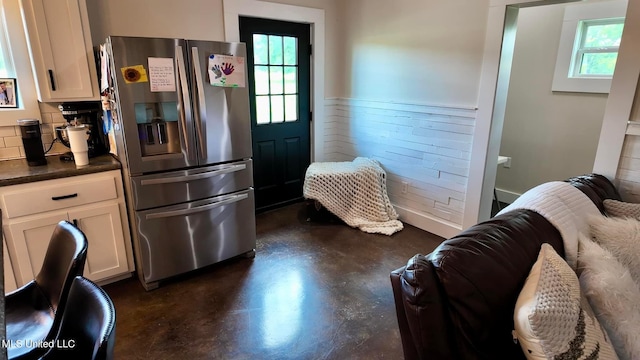 kitchen featuring a wealth of natural light, stainless steel fridge with ice dispenser, white cabinetry, and tasteful backsplash