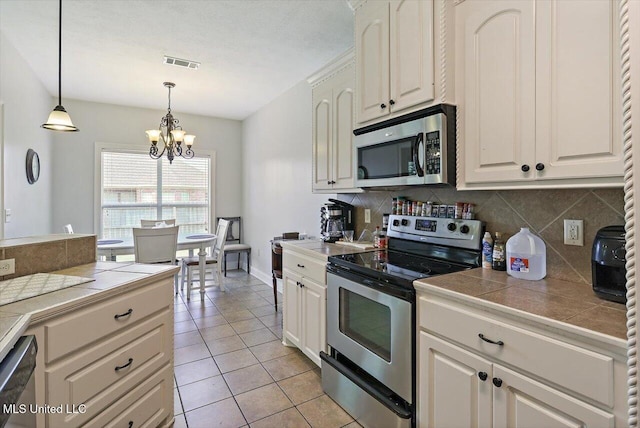 kitchen featuring visible vents, decorative backsplash, pendant lighting, an inviting chandelier, and stainless steel appliances
