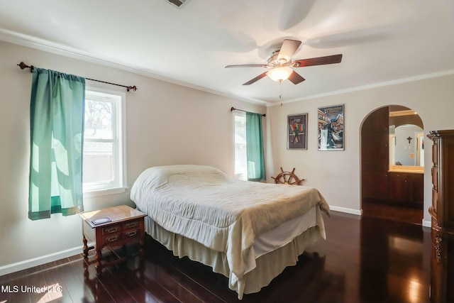 bedroom with arched walkways, dark wood-type flooring, ornamental molding, and baseboards