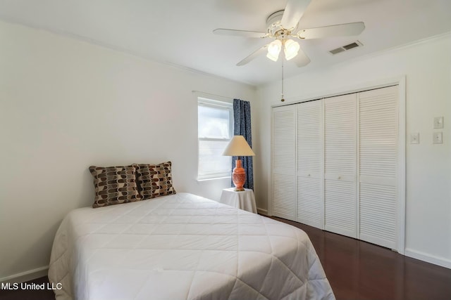 bedroom with visible vents, baseboards, ceiling fan, wood finished floors, and a closet