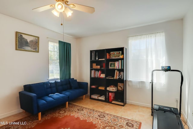 living area featuring light tile patterned floors, baseboards, and a ceiling fan