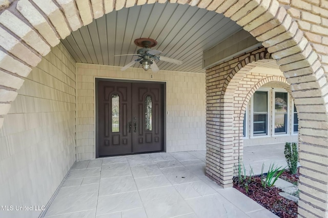 property entrance with ceiling fan and brick siding